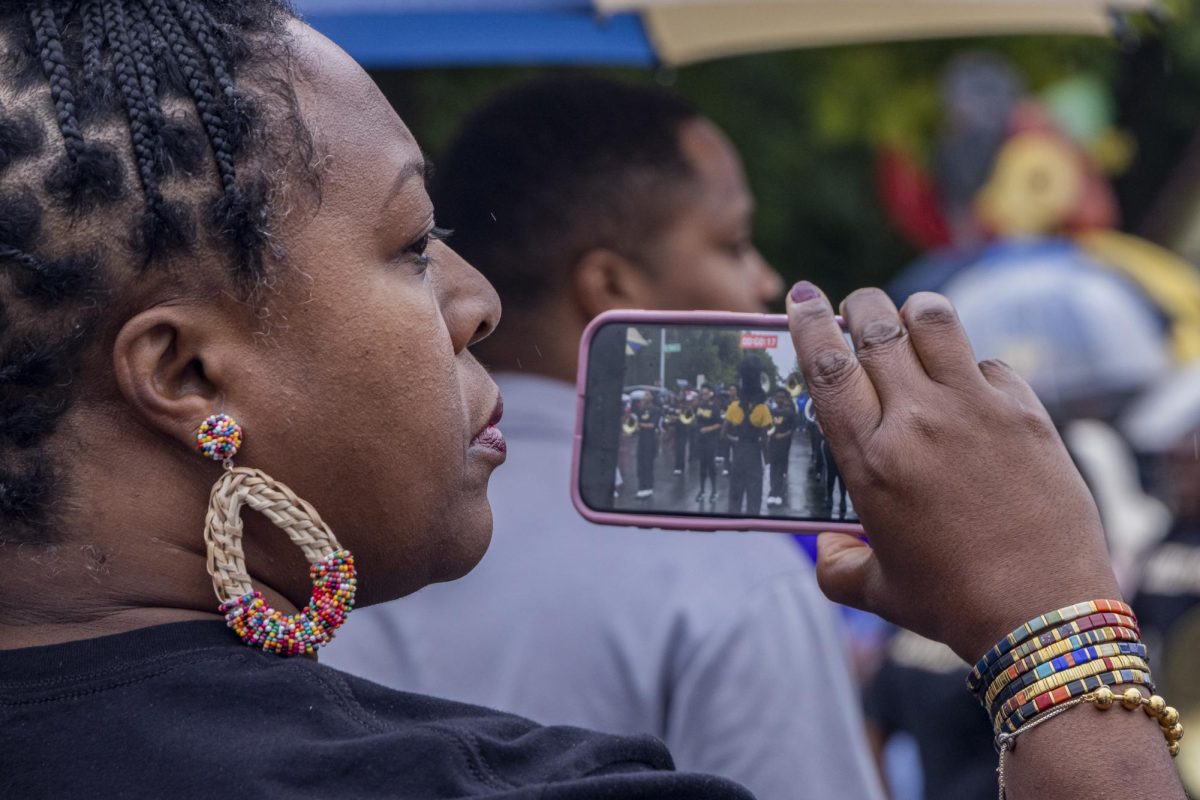 An attendee records Central High School's Marching Band during the parade on Saturday, Sep. 6, 2025, at the 36th annual Lexington Roots & Heritage Festival in Lexington, Ky. Photo by Brooke Johnson | Staff