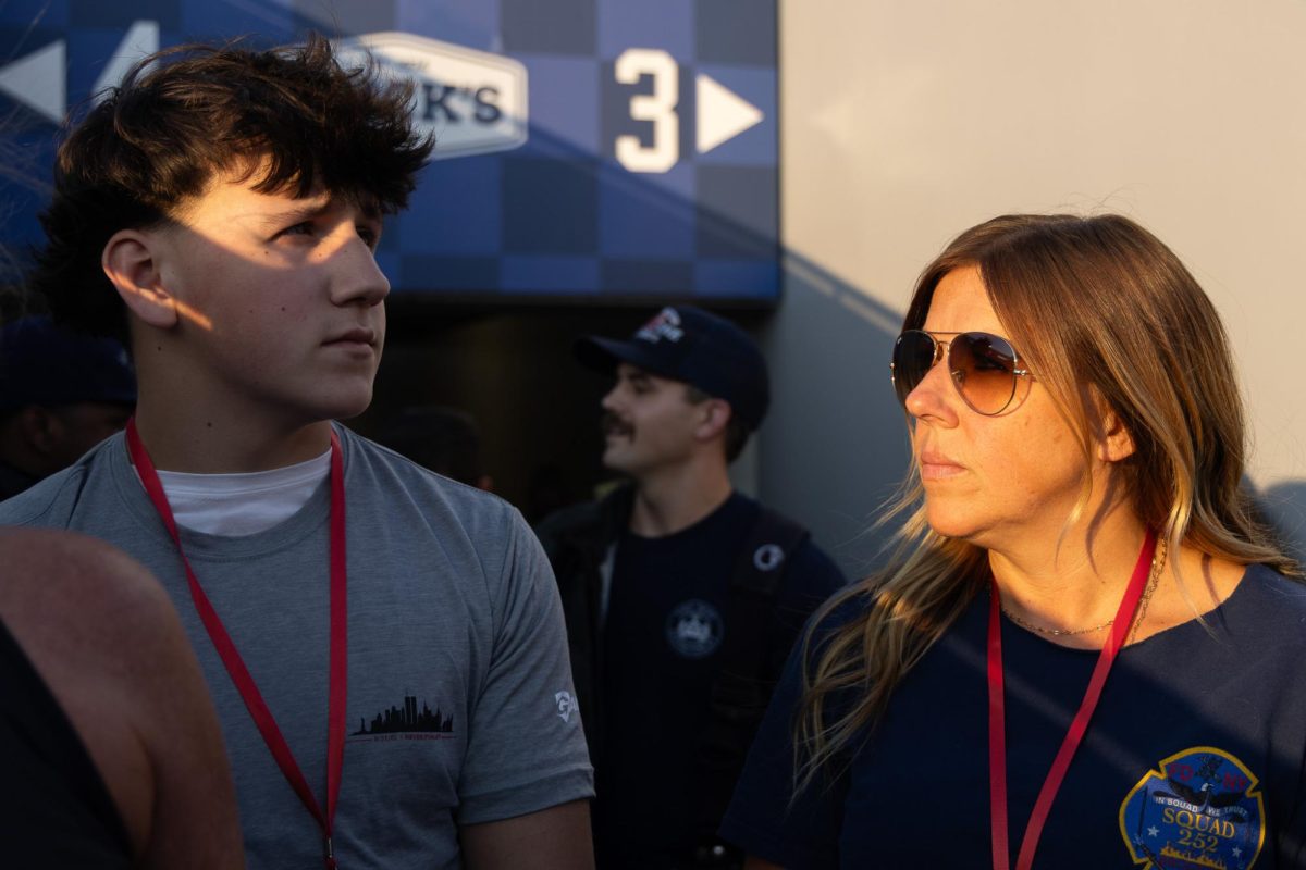 Kristen Kuveikis, right, looks at her son, Aiden Hall, left, during the 9/11 Memorial Stair Climb moment of silence on Thursday, Sept. 11, 2025, at Kroger Field in Lexington, Ky. Kristen said her son looks just like her late father, Thomas Kuveikis, who died on Sept. 11 while working as a firefighter. Photo by Isabella Sepahban | Staff