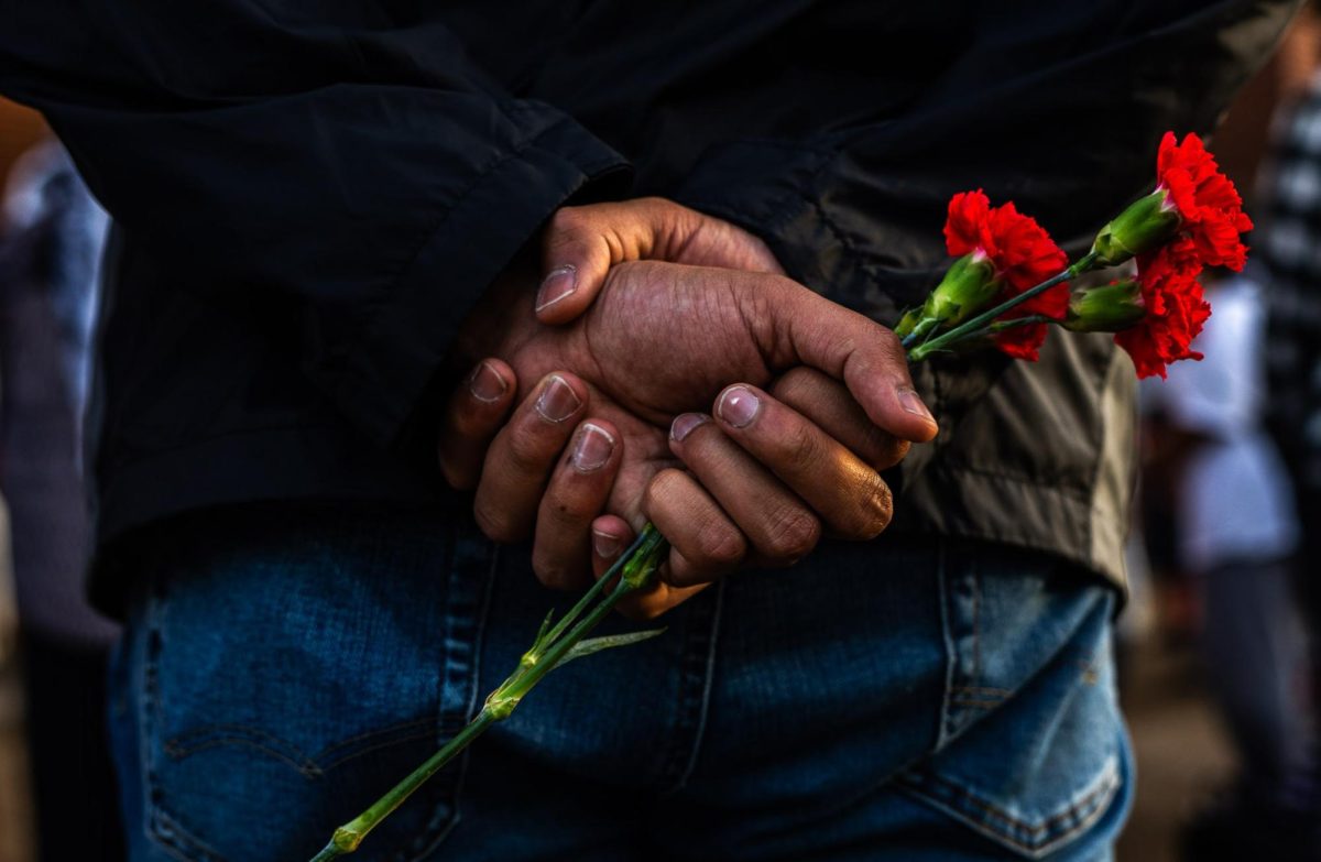 An attendee holds a flower behind his back during the Two Years Too Many protest on Tuesday, Oct. 7, 2025, outside the William T. Young Library in Lexington, Ky. Photo by Will Luckett | Staff