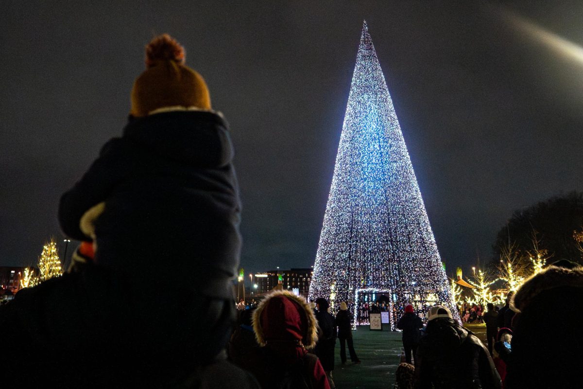 A young boy sits on his father’s shoulders as he watches the tree turn on at the Winter Village on Thursday, Dec. 4, 2025, at Gatton Park on the Town Branch in Lexington, Ky. Photo by Will Luckett | Staff