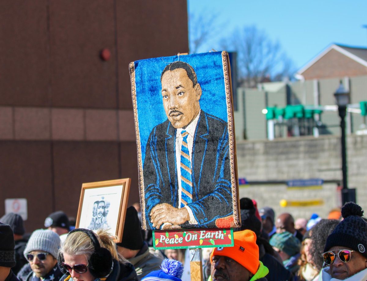An attendee of the 2026 Martin Luther King Jr. Holiday Freedom March holds a sign depicting Martin Luther King Jr. while walking down W Vine Street in downtown Lexington on January 19, 2026.   | Photo by Holly Netzley.

